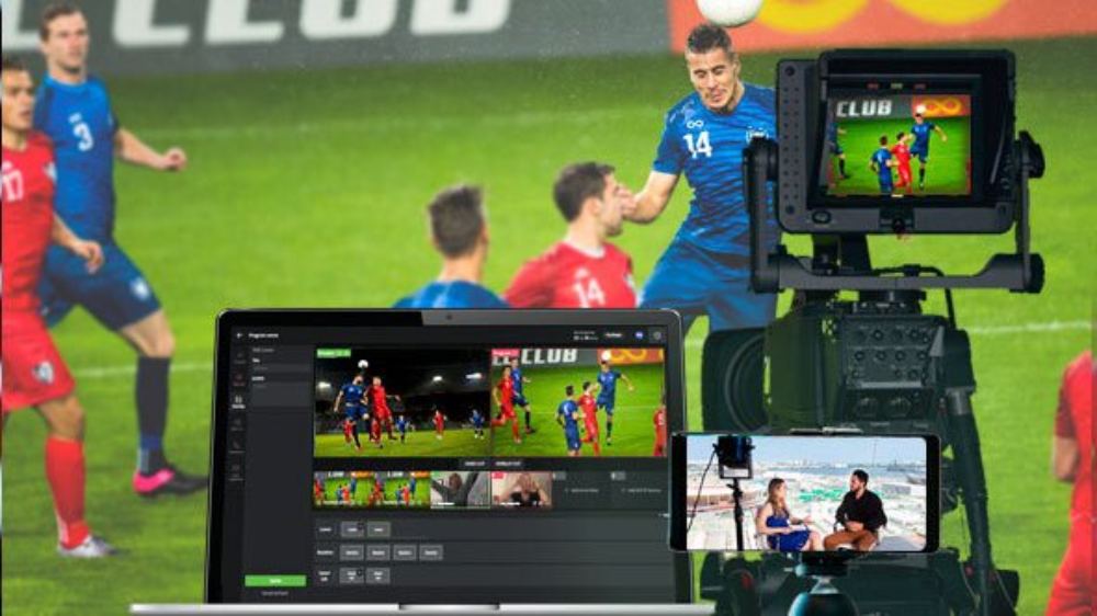 A laptop with sports broadcasting,  a smartphone and video camera, filming a football match